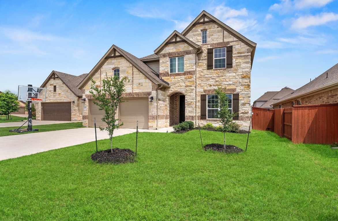 a front view of a house with a yard and green space