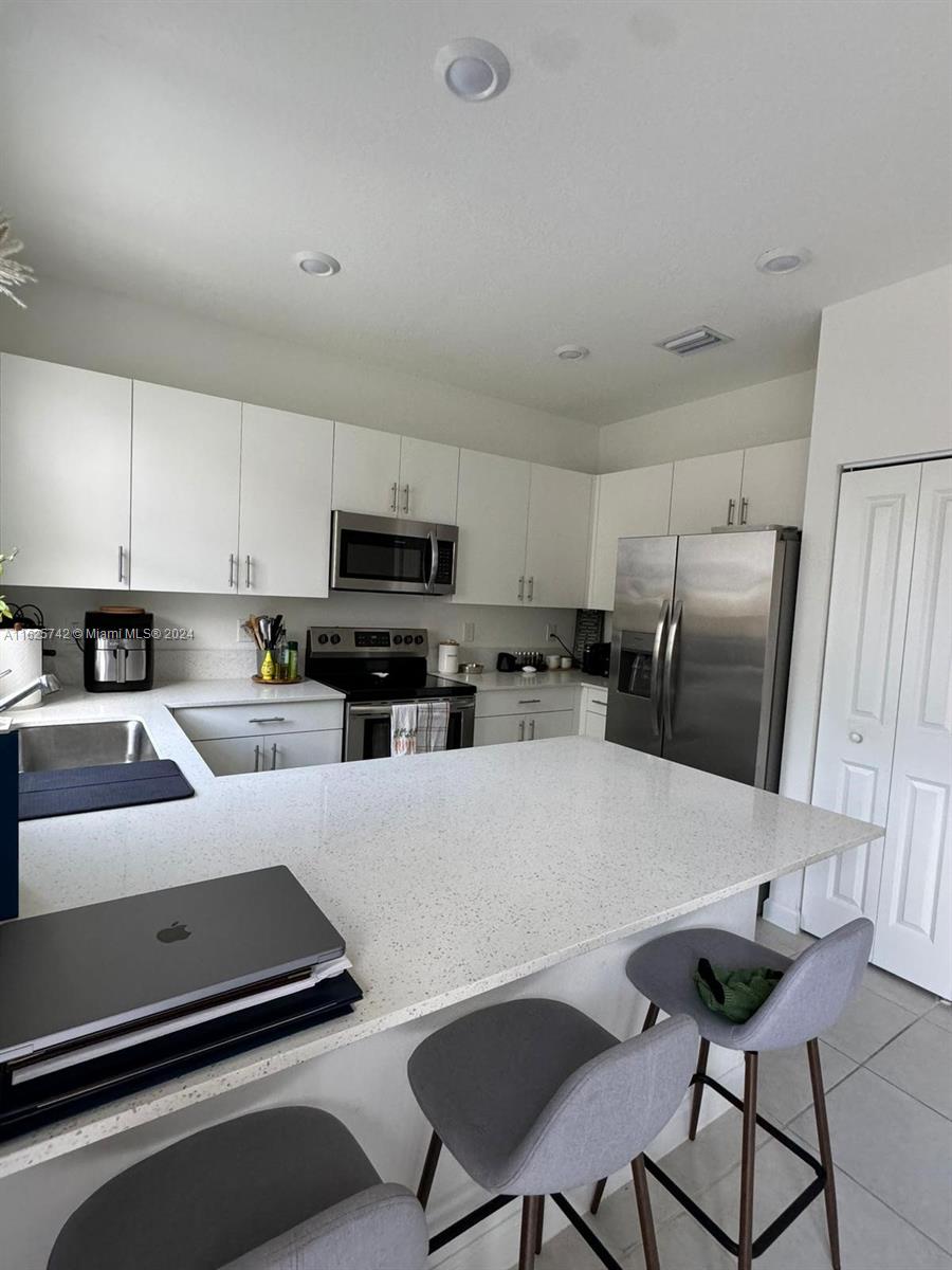 a kitchen with stainless steel appliances a stove a refrigerator a sink a dining table and chairs