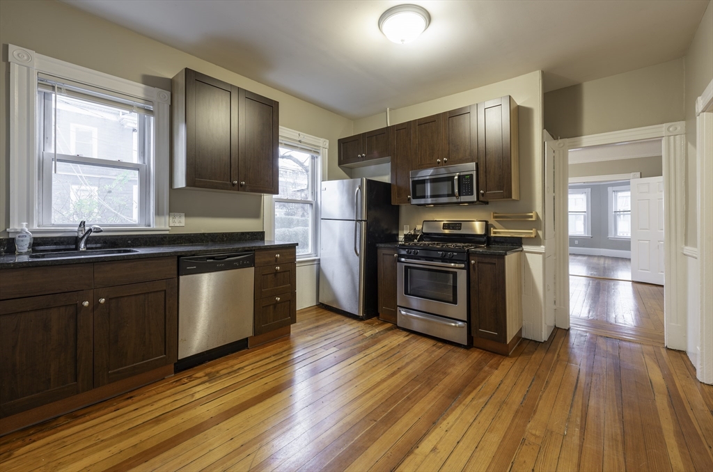 a kitchen with wooden floors and stainless steel appliances