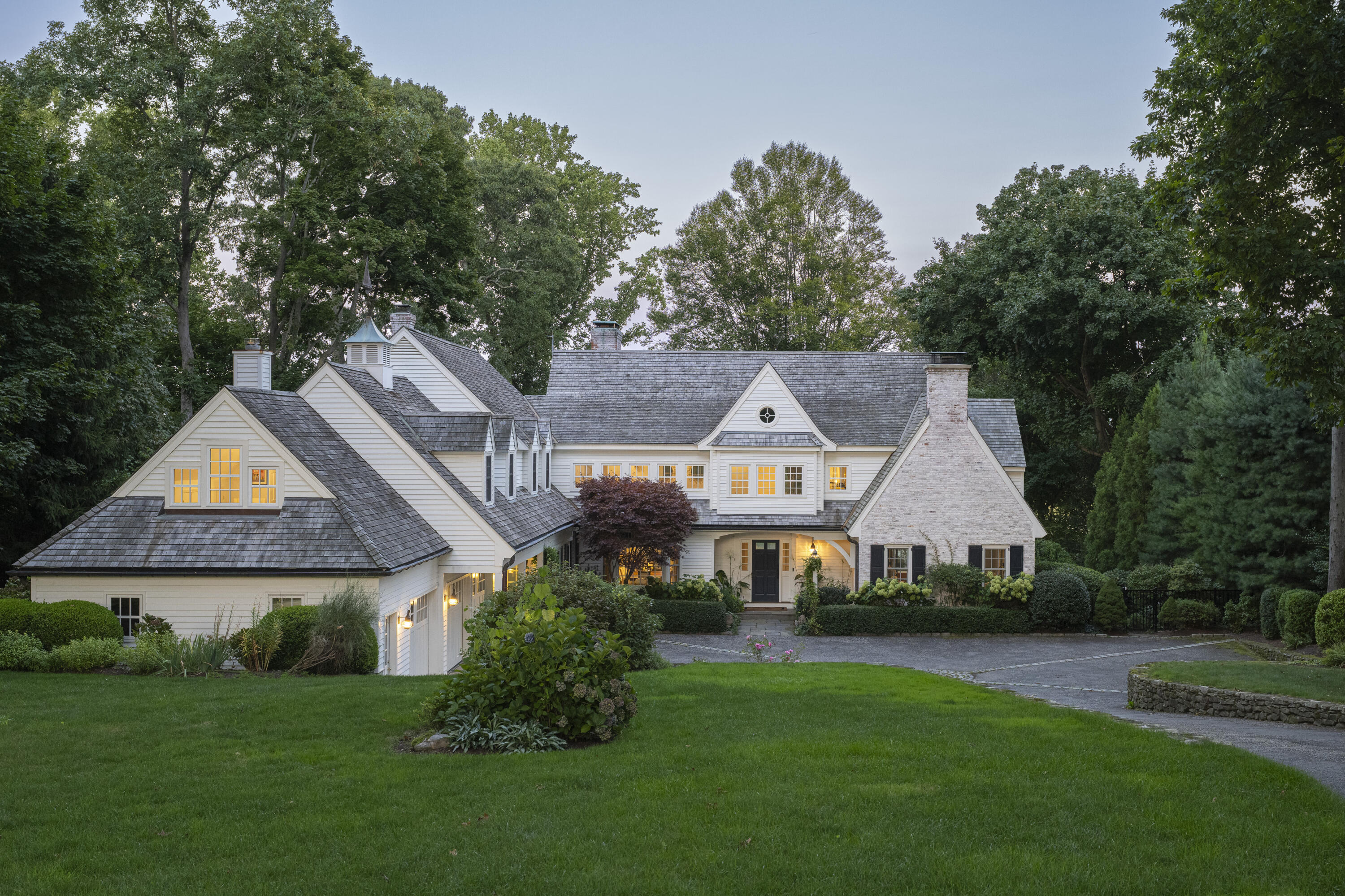 a front view of a house with a garden and trees