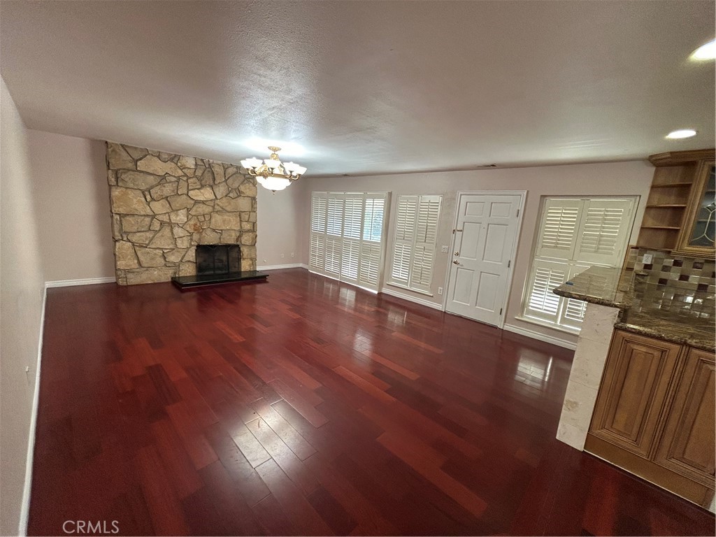 a view of an empty room with wooden floor and a fireplace