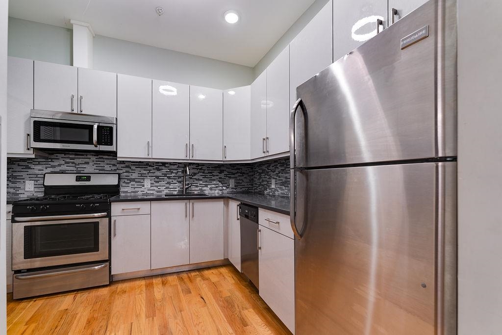 a kitchen with stainless steel appliances granite countertop a refrigerator and a stove top oven