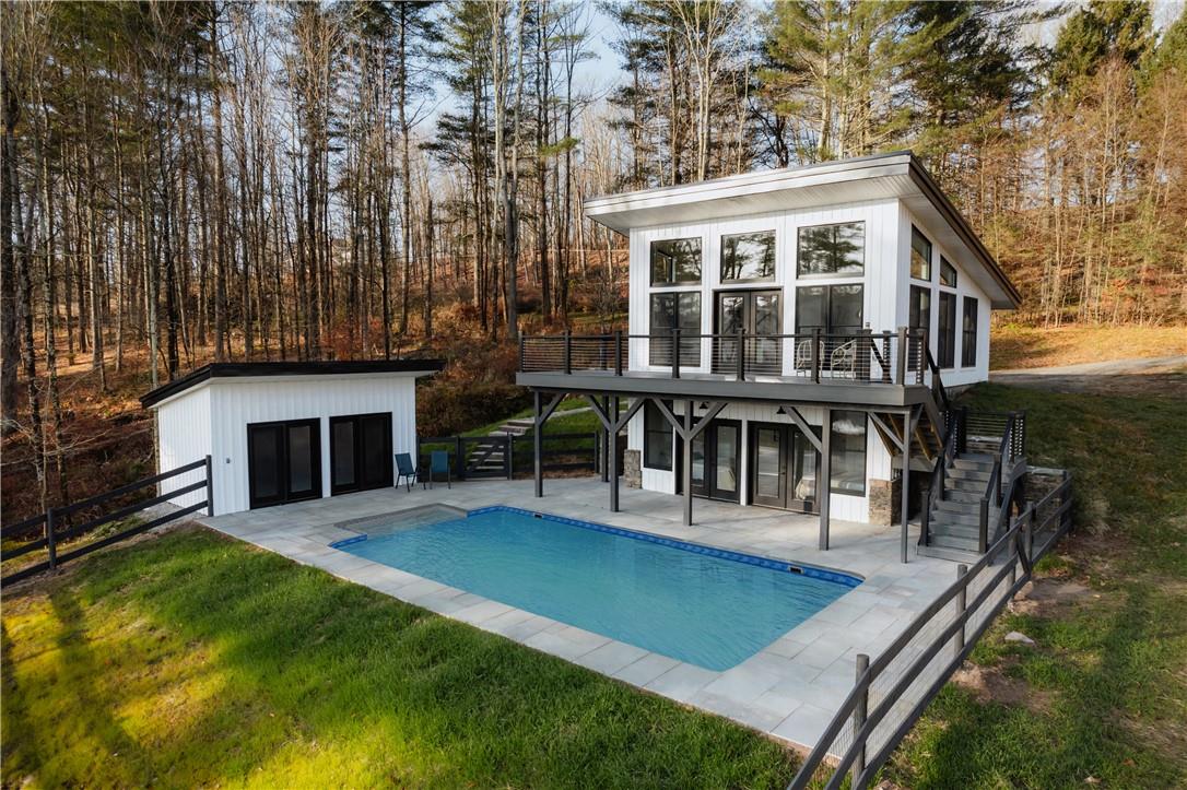 Rear view of property featuring a patio, an outbuilding, and a pool side deck