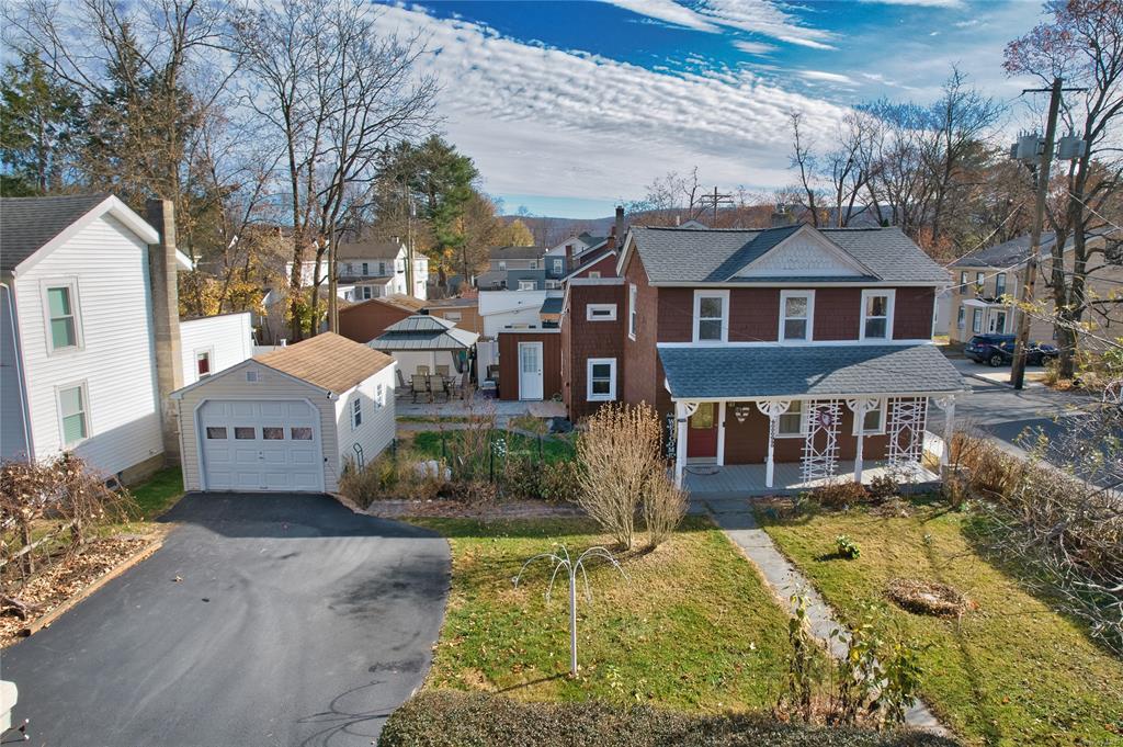 View of front of house featuring covered porch, a garage, an outdoor structure, and a front yard