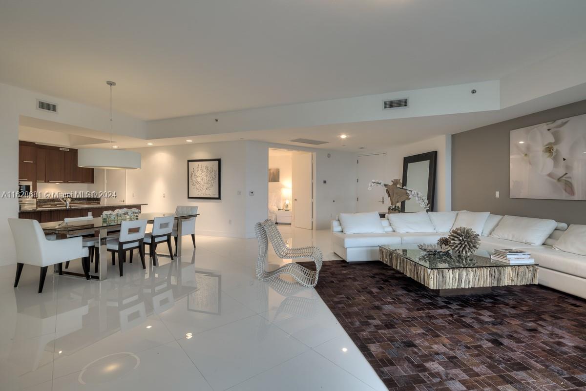 a living room with furniture wooden floor and kitchen view