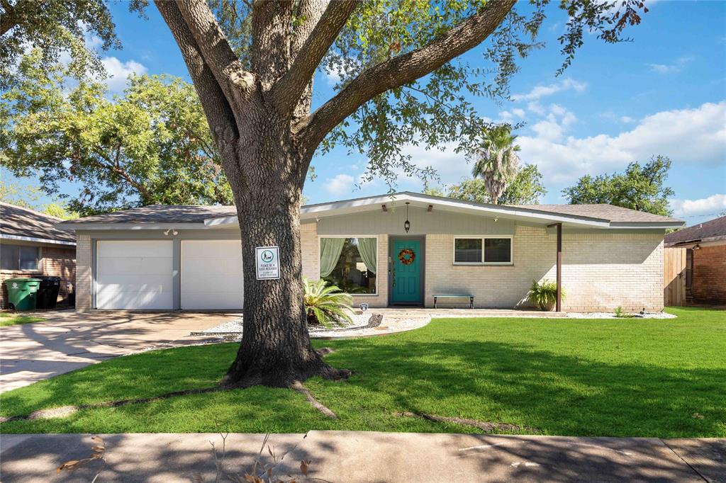 The front of this home boasts elegant brickwork, tall windows, and a welcoming porch framed by lush landscaping, creating an inviting and sophisticated curb appeal.