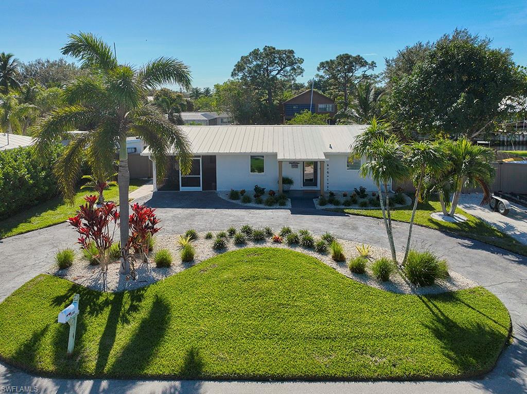 View of front of home with front lawn and wrap around driveway