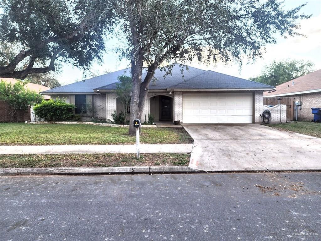 a front view of a house with yard and large tree