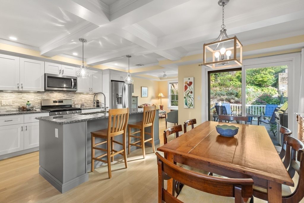 a kitchen with stainless steel appliances granite countertop a dining table chairs refrigerator sink and cabinets