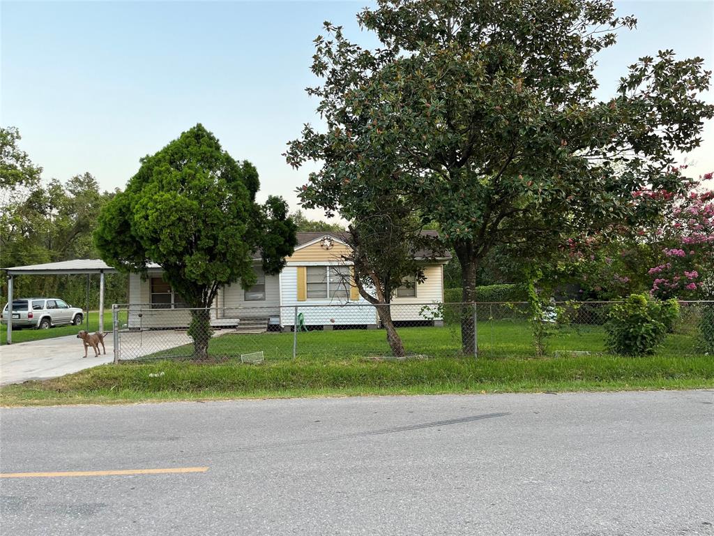 a view of a house with a yard and large trees