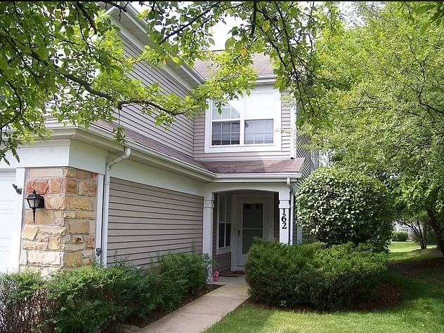 a front view of a house with plants and garden