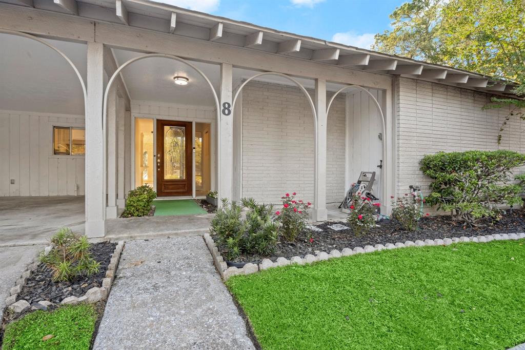 Charming single-story home featuring a covered entryway with arches, a decorative front door, and a well-maintained lawn with landscaping.