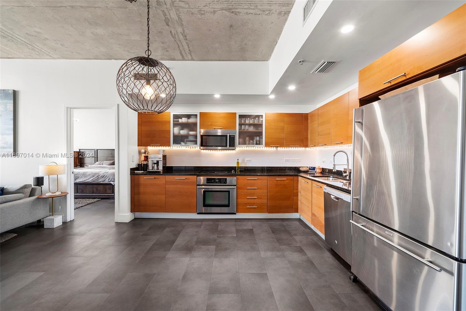 a large kitchen with stainless steel appliances kitchen island granite countertop a table and a chandelier