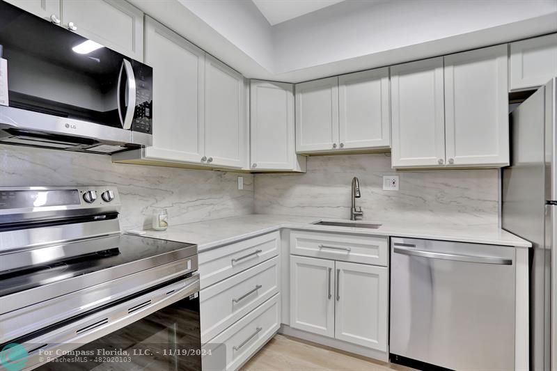 a kitchen with white cabinets stainless steel appliances and sink