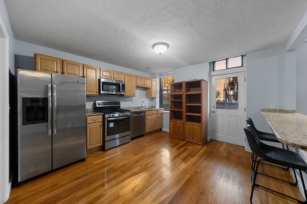 a kitchen with stainless steel appliances wooden floor a refrigerator and a stove top oven