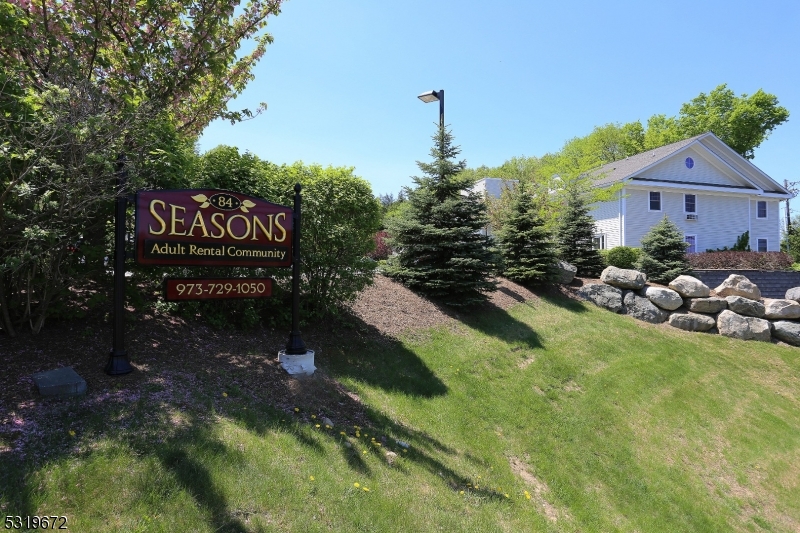 a sign that is sitting in front of a house with a yard