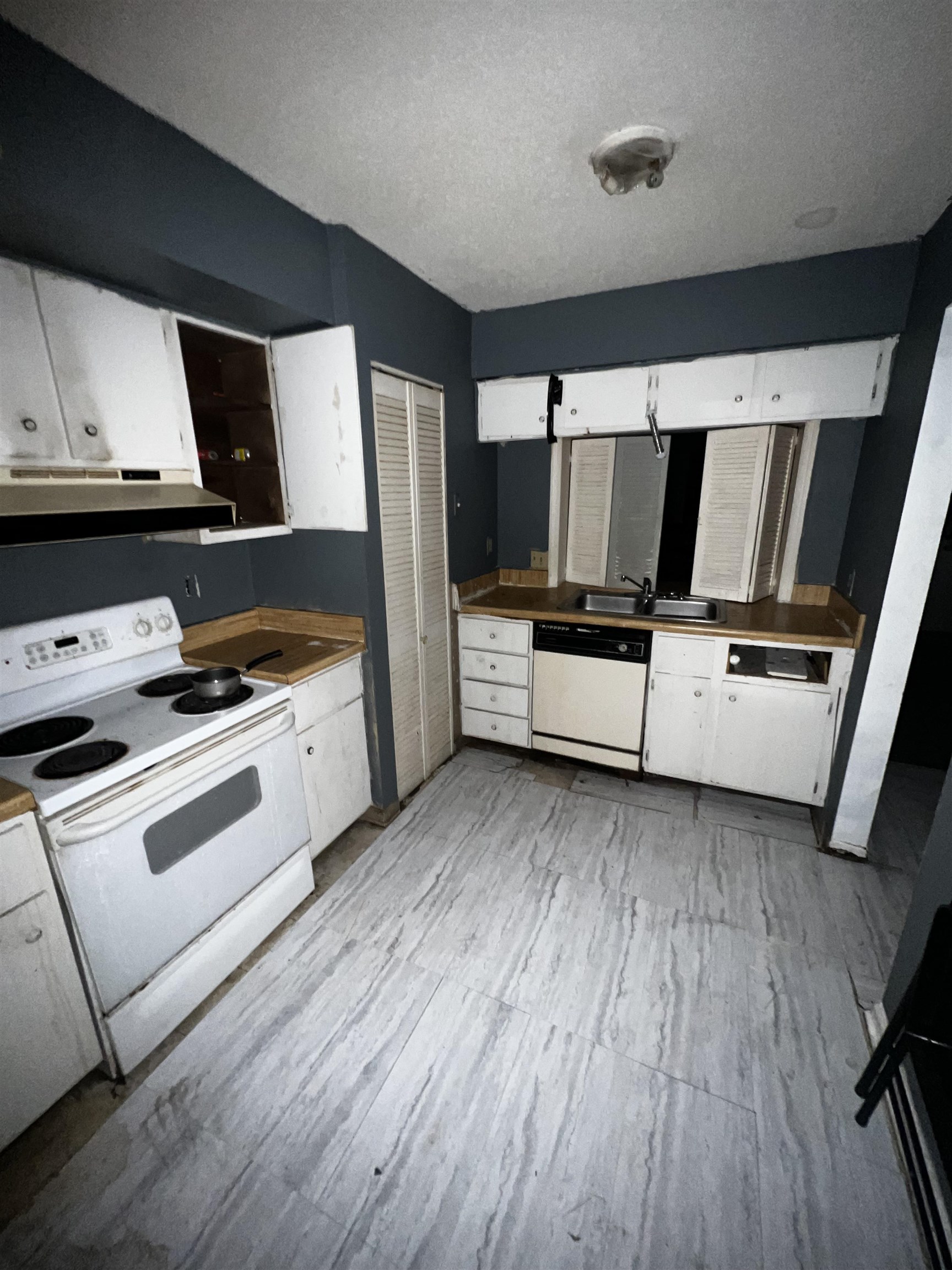 a white kitchen with wooden floor and white stainless steel appliances