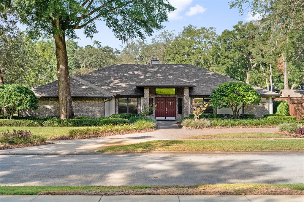 Front of home featuring circular paver driveway leading to beautiful double entry doors