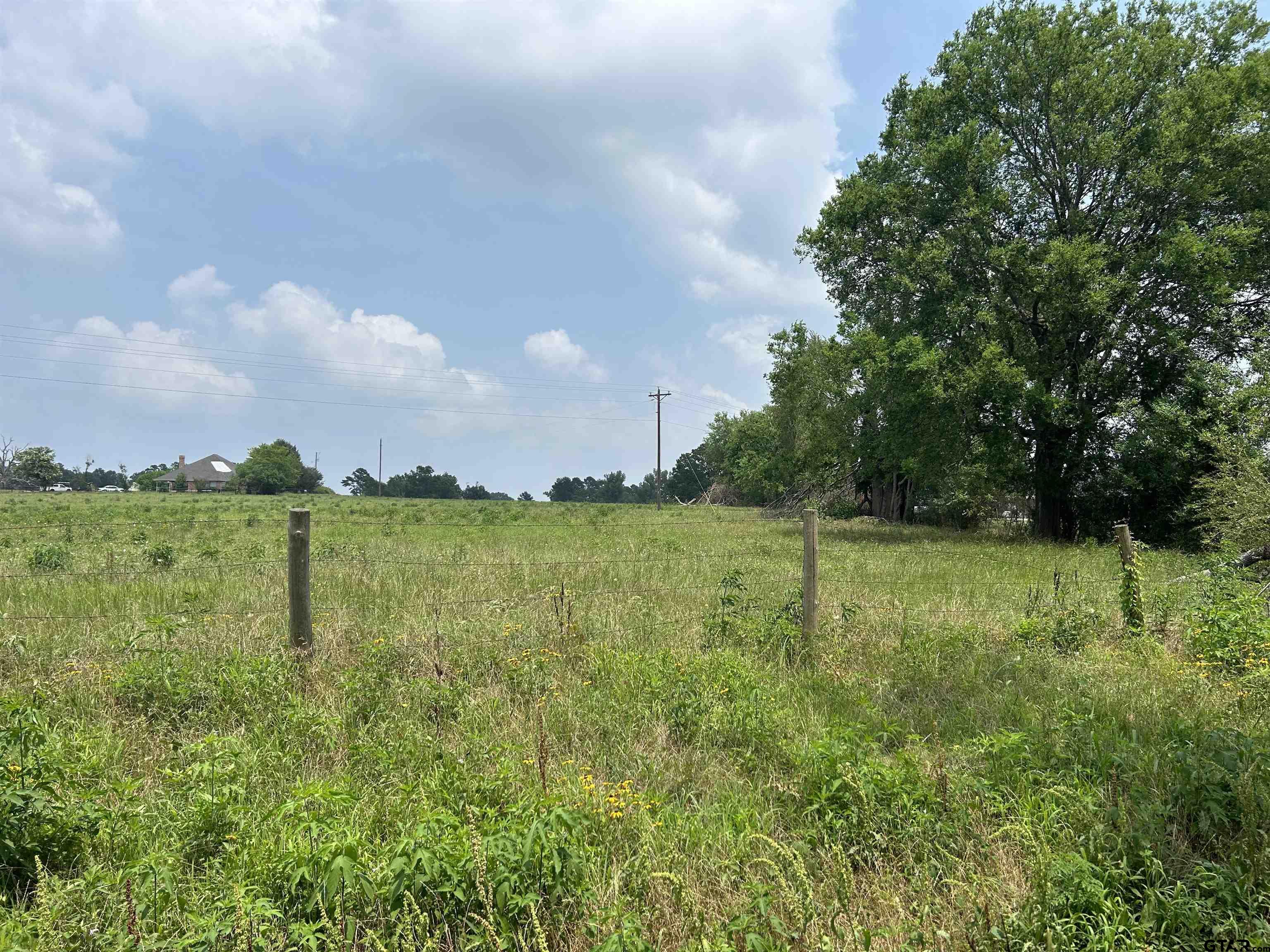 a view of a green field with wooden fence