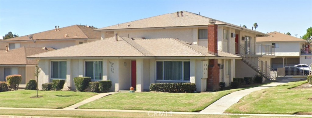 a view of a brick house with many windows next to a yard