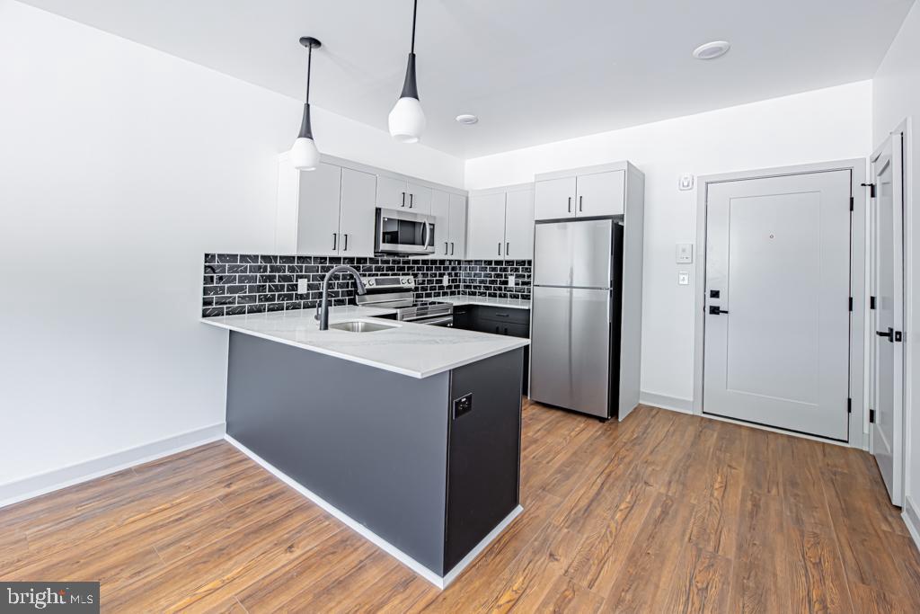 a kitchen with a refrigerator a sink and wooden floor