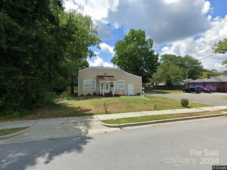 a view of a house with a big yard plants and large trees