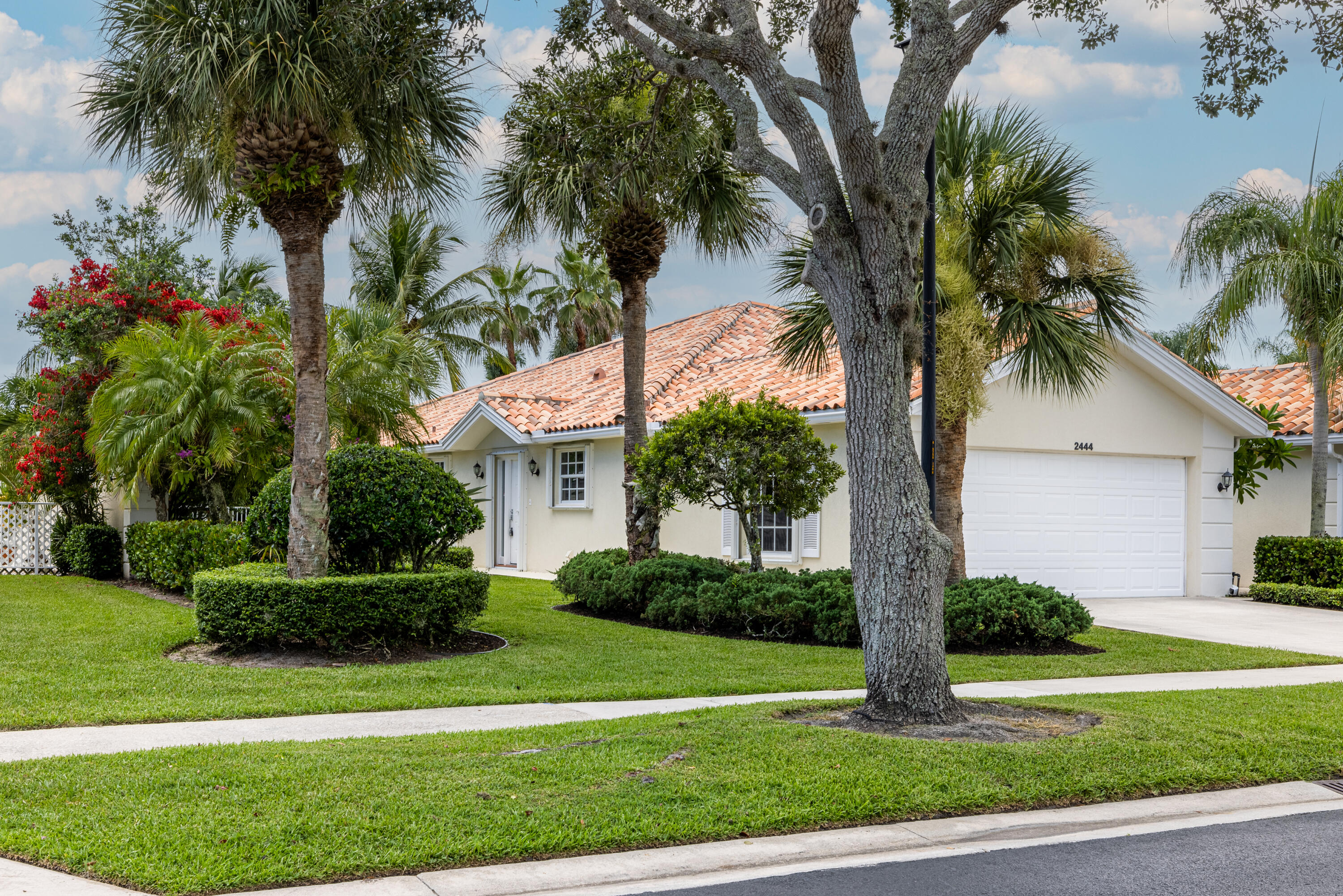 a front view of a house with a yard and palm trees