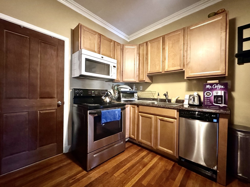 a kitchen with granite countertop wooden cabinets stainless steel appliances and a window