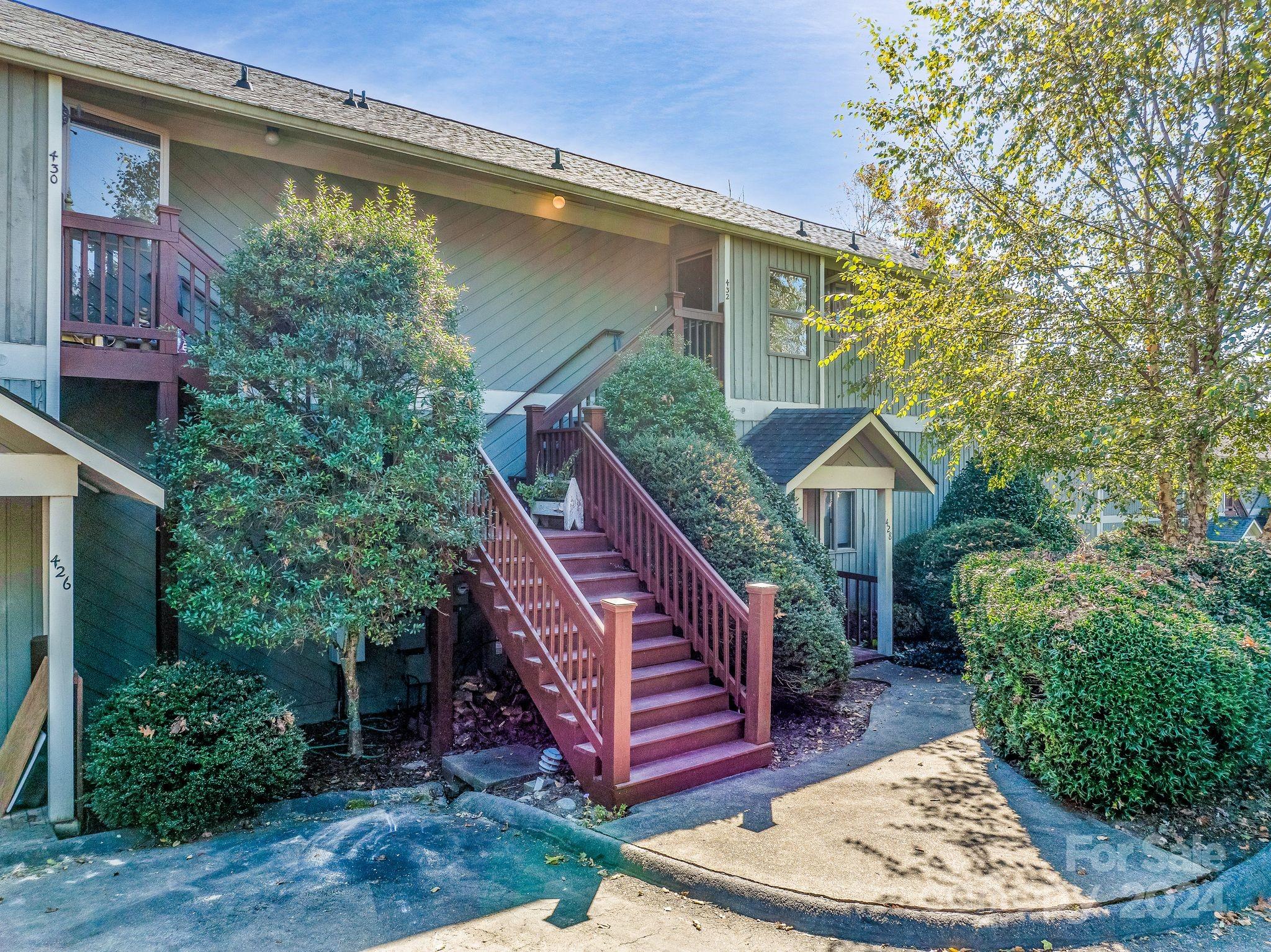 a view of a house with a balcony wooden stairs and a yard