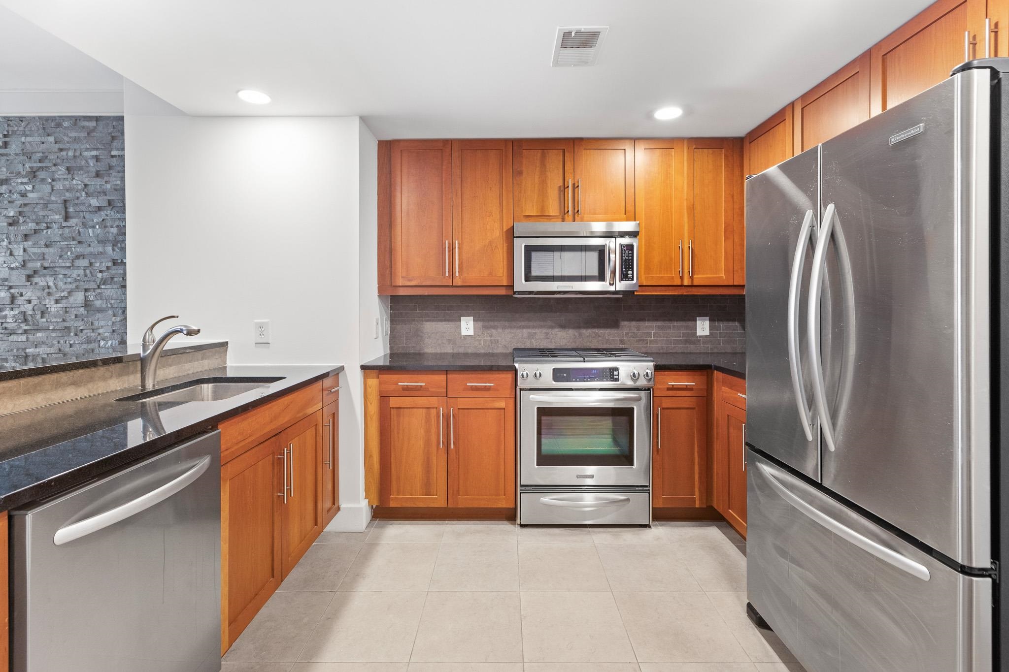 a kitchen with stainless steel appliances granite countertop a refrigerator stove and sink