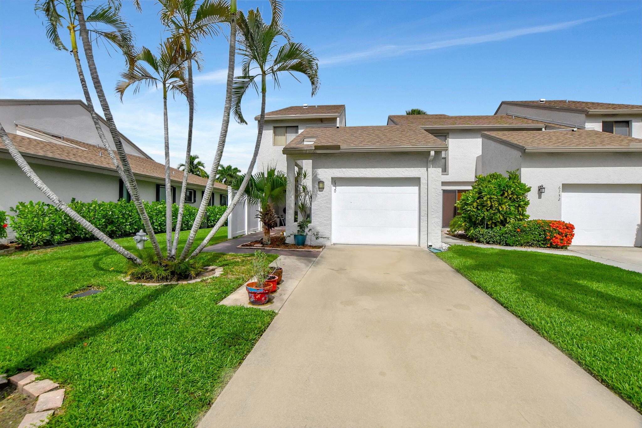 a front view of a house with a yard and potted plants