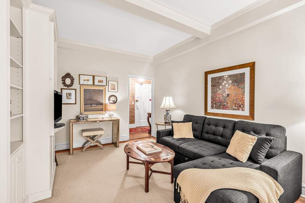 a living room with furniture a couch and dresser with wooden floor