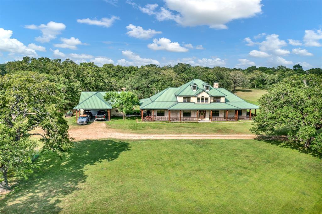 a view of a house with a big yard and large trees