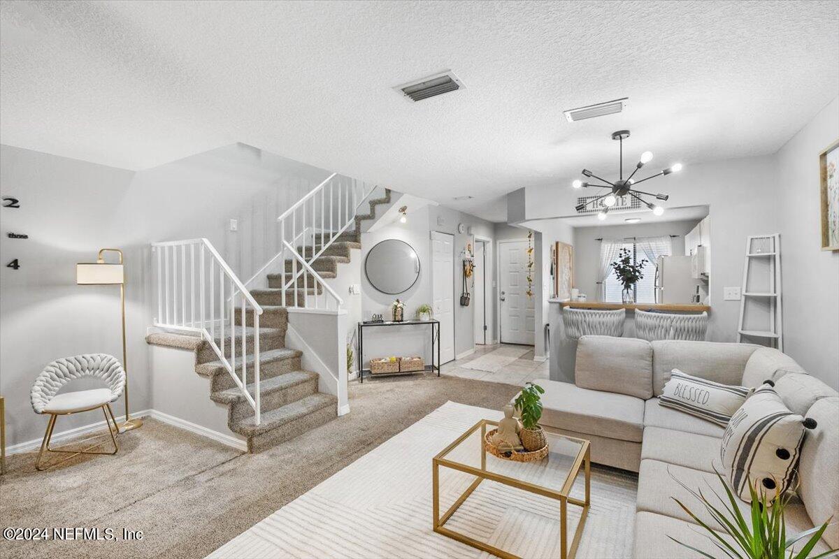 a living room with furniture a chandelier and a dining table with wooden floor