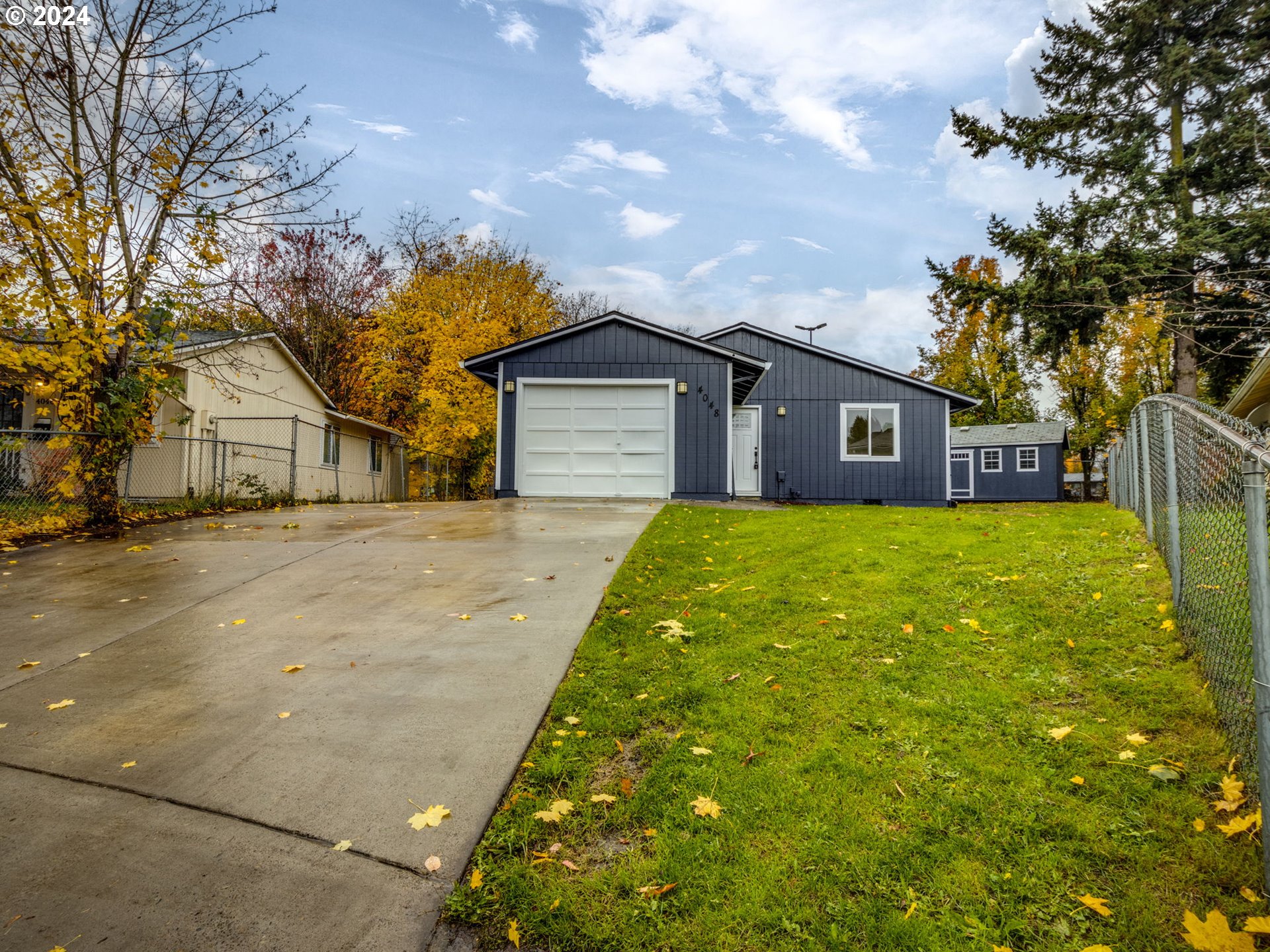 a front view of a house with a big yard and large tree