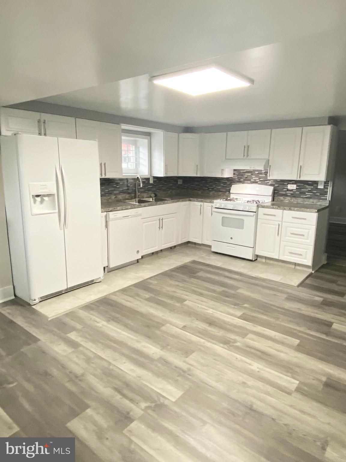 a large white kitchen with kitchen island white cabinets and refrigerator