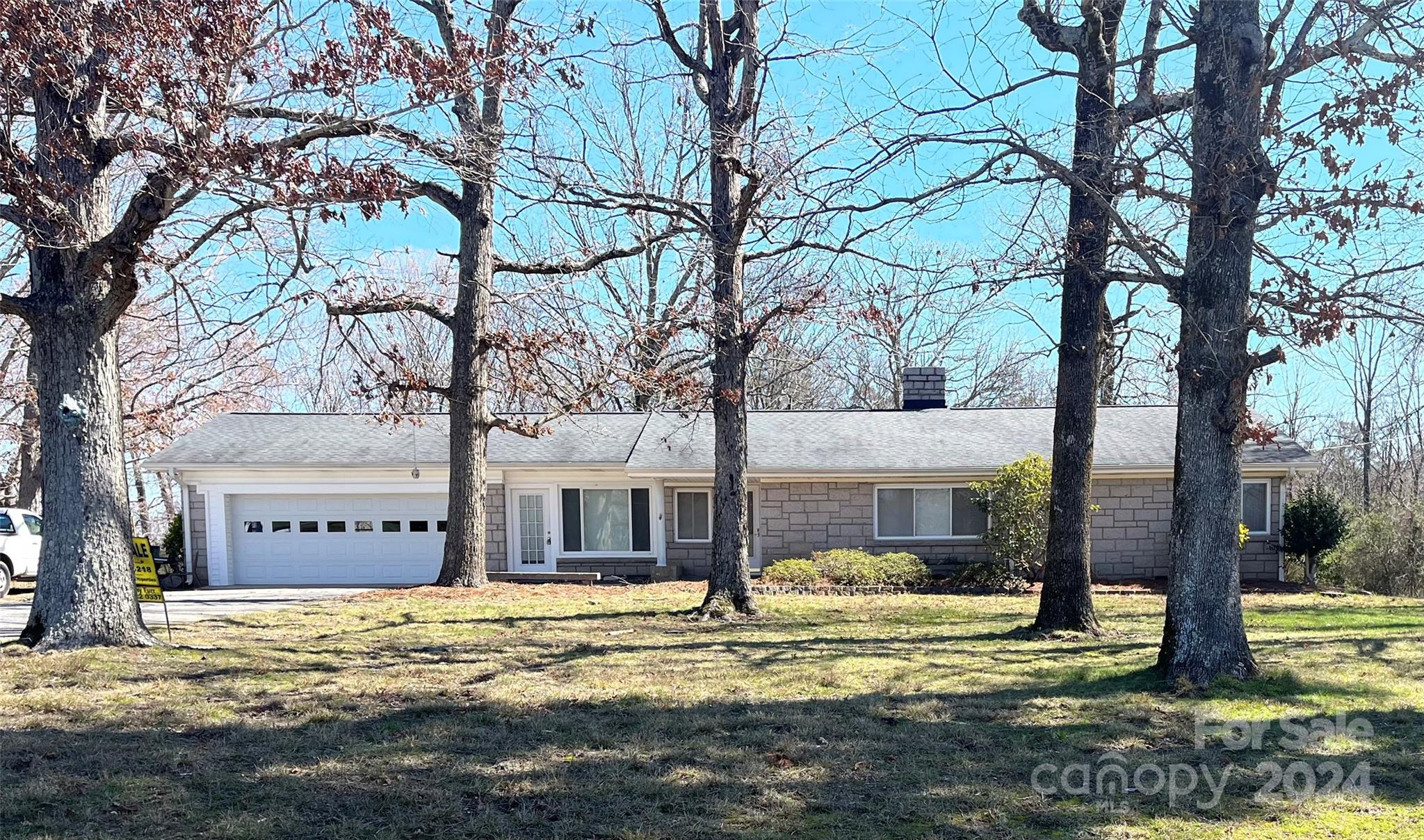 a view of a house with a large tree next to a yard