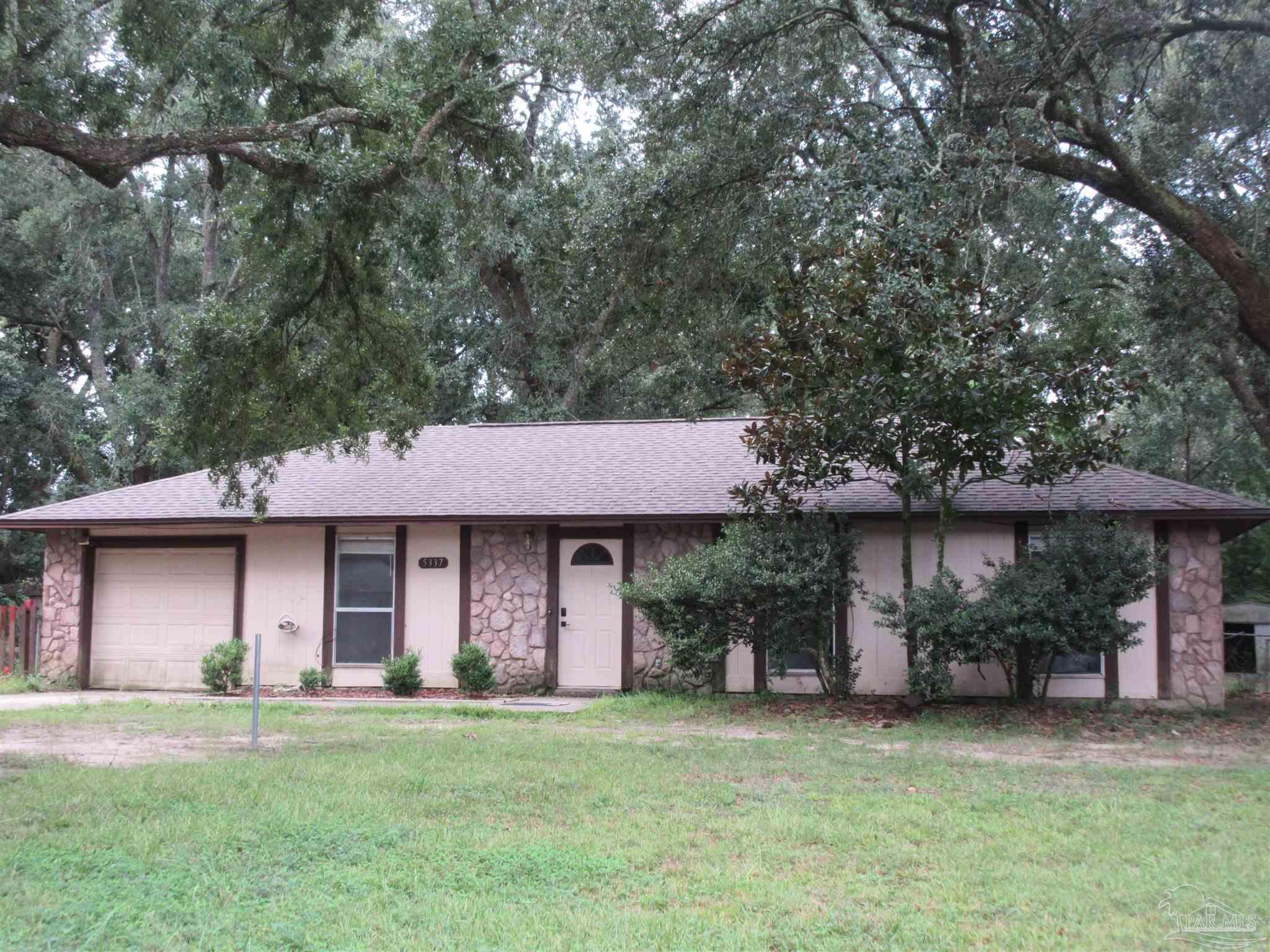 a front view of a house with a garden and trees