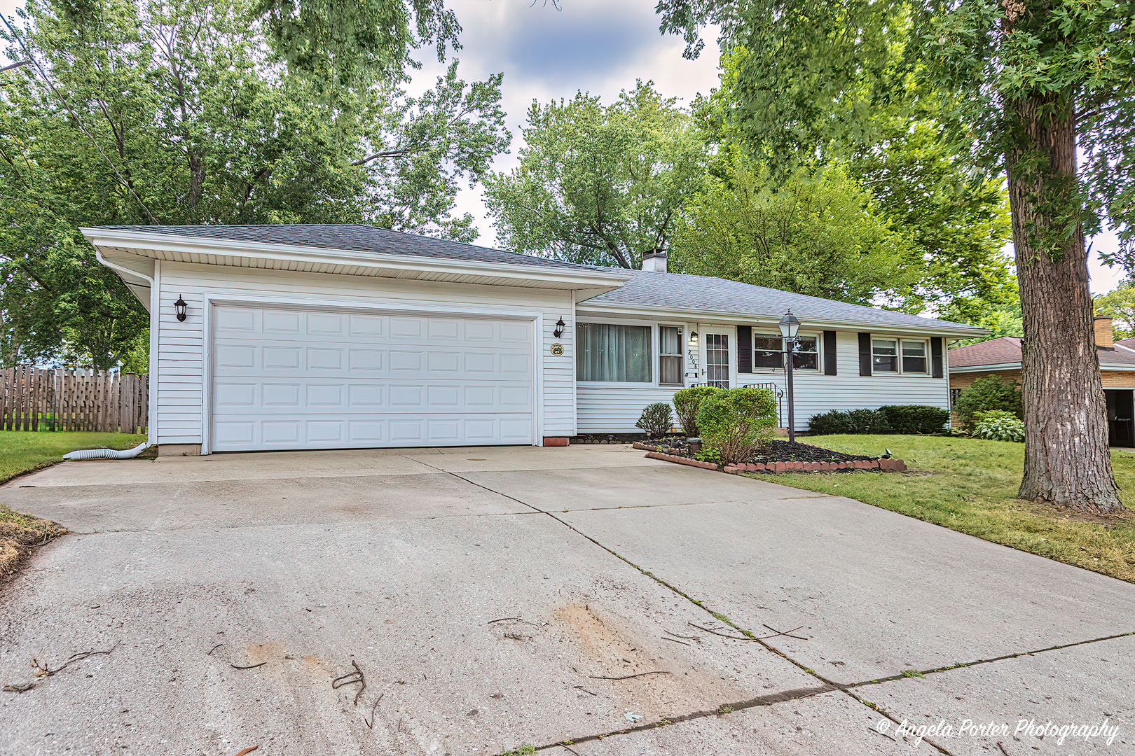 front view of house with a yard and trees all around