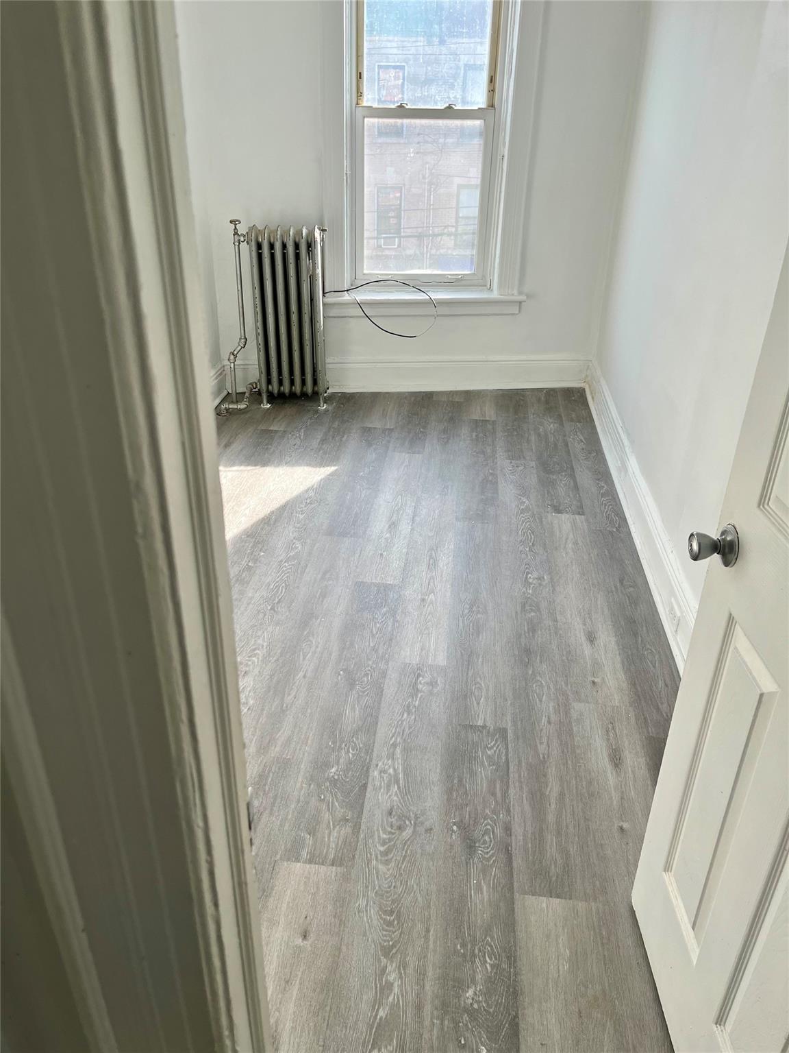 Spare room with radiator heating unit and hardwood / wood-style flooring