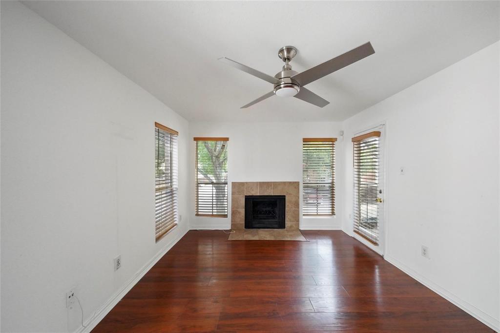 an empty room with wooden floor a ceiling fan and windows