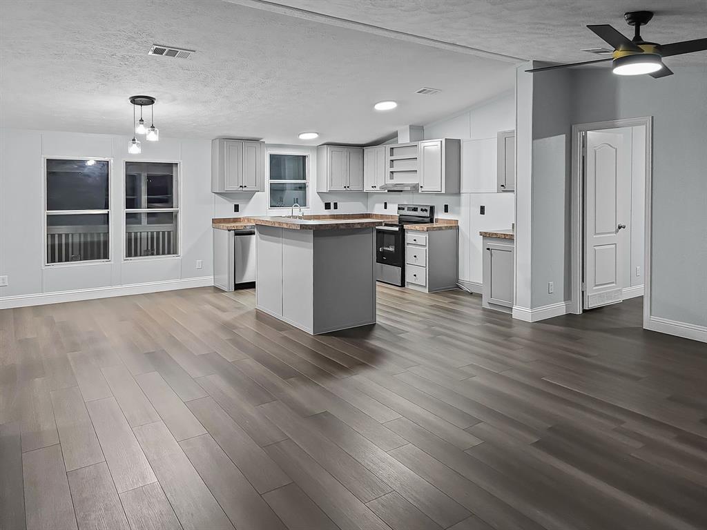 a kitchen with stainless steel appliances kitchen island wooden floors granite counter tops and a window