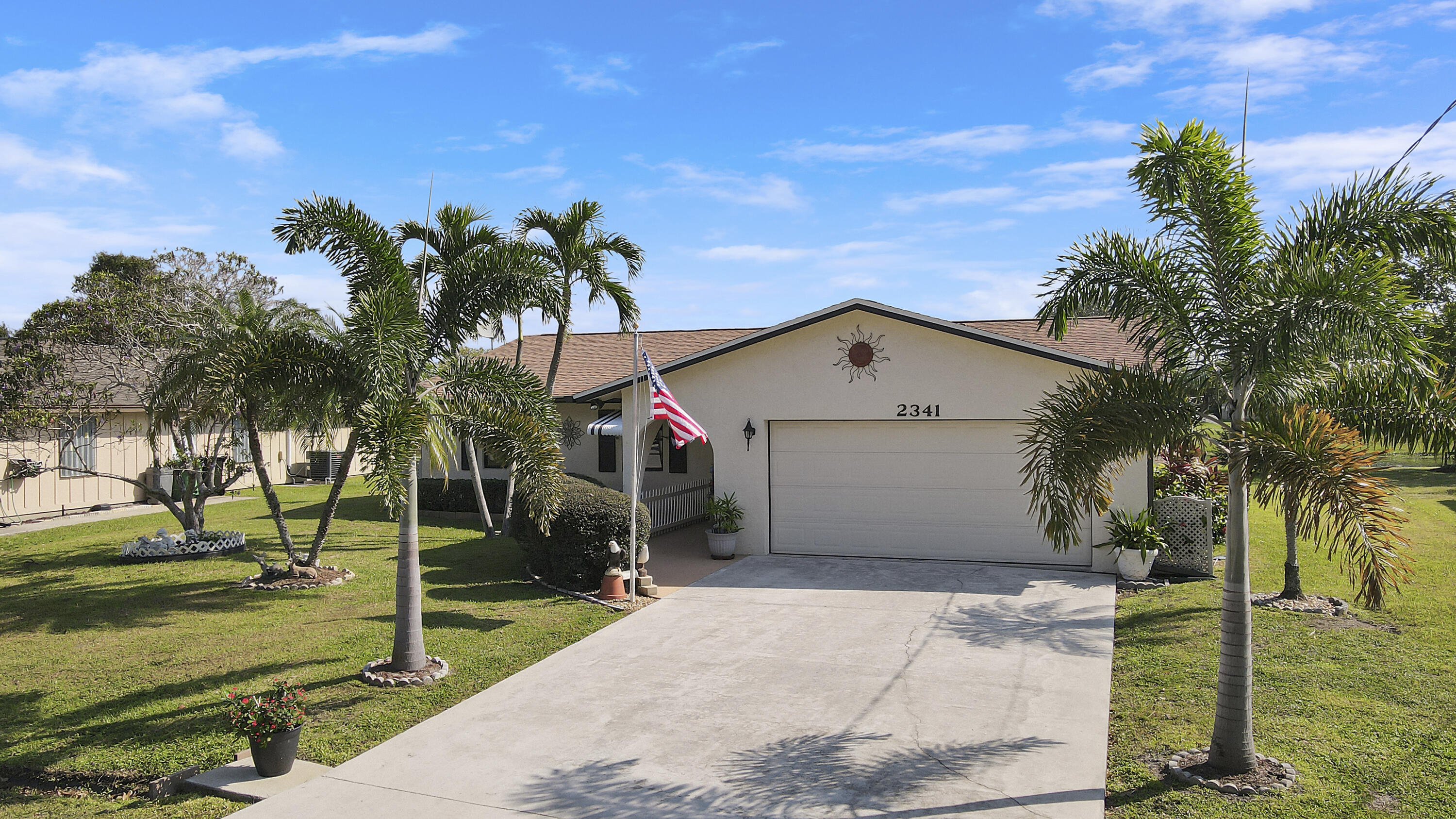 a view of a house with a yard and palm trees