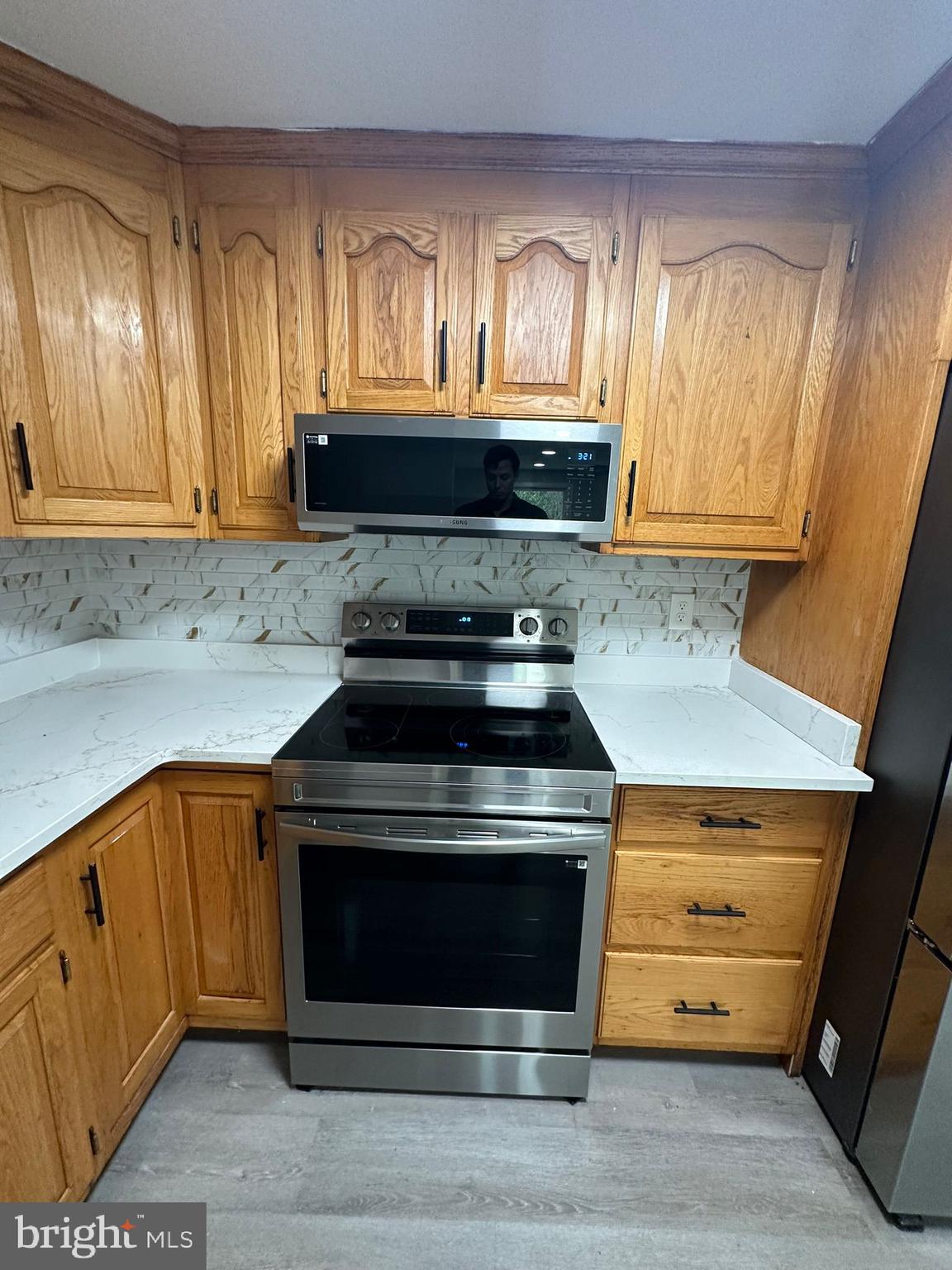 a kitchen with granite countertop wooden cabinets and a stove top oven