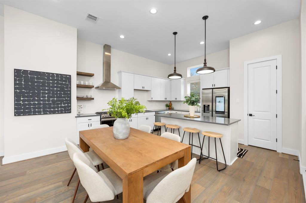 a kitchen with stainless steel appliances kitchen island granite countertop a table chairs and a wooden floor