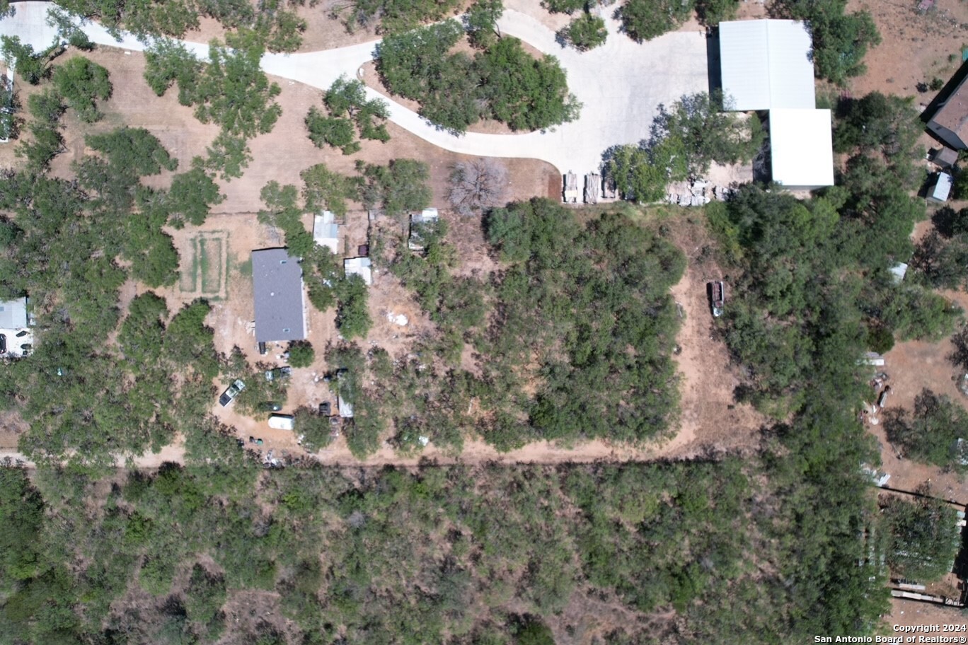 an aerial view of residential house with outdoor space and trees all around