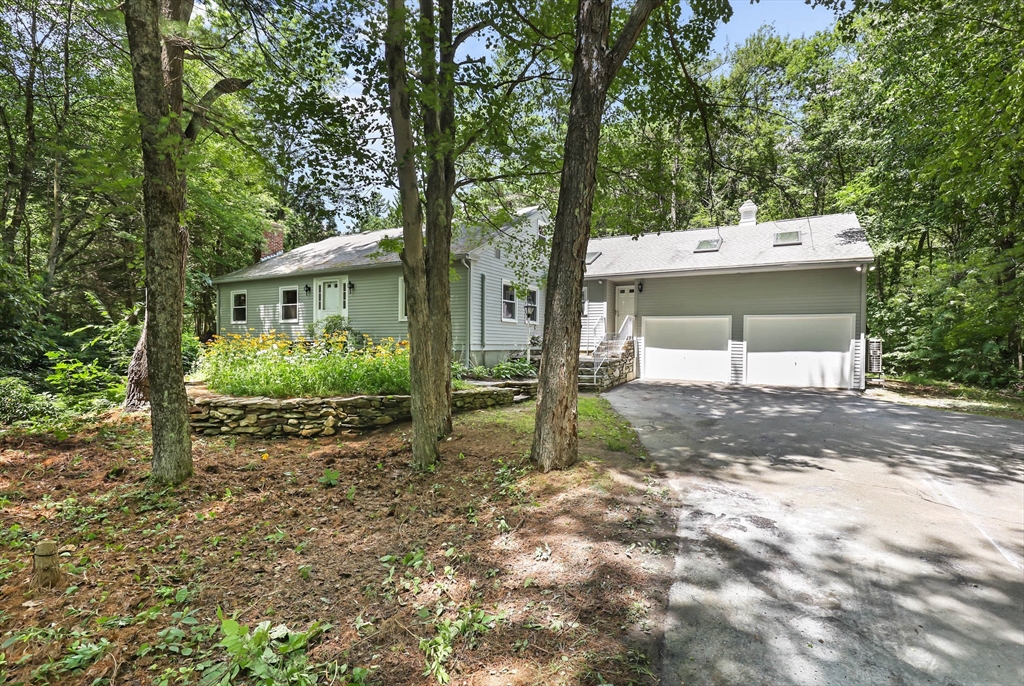 a view of a house with a yard and large trees