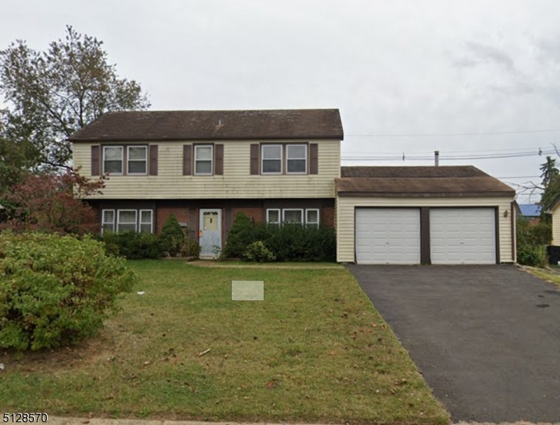 a front view of a house with yard and parking