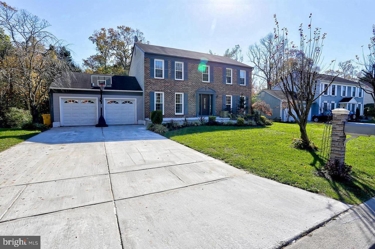 a view of a brick house with a yard and large trees