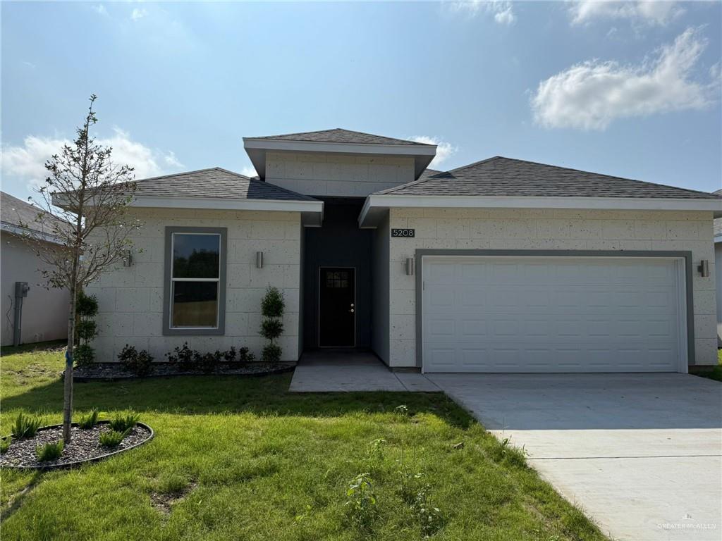 View of front of property with a front yard and a garage